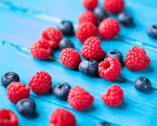 Blueberries and raspberries on blue wooden table - Photo, image