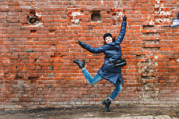 smiling girl was photographed in a jump on a brick wall background - Fotó, kép