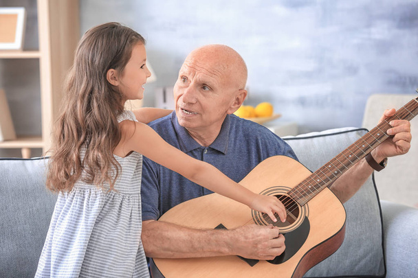 Senior man with granddaughter playing guitar  - Photo, Image