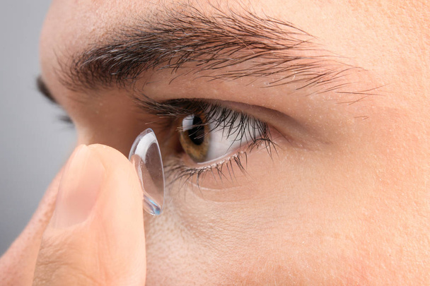 Young man putting contact lens  - Foto, Imagen
