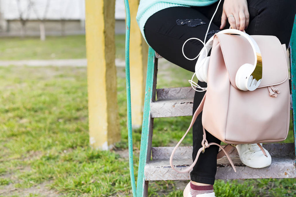 Pernas femininas em jeans e tênis, mochila, fones de ouvido e telefone inteligente
 - Foto, Imagem