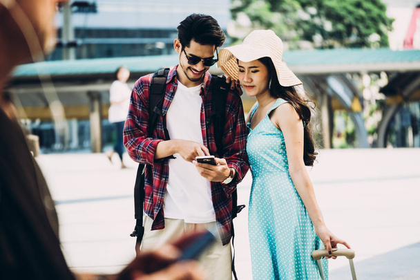 Néhány ázsiai utazók séta a város utcája, és nézett érdekes elhelyez-hoz utazik-ból szúró telefon. Nyaralás és a technológia koncepció - Fotó, kép