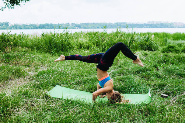 Sportive young woman in sportswear doing yoga exercise outdoors - Фото, зображення