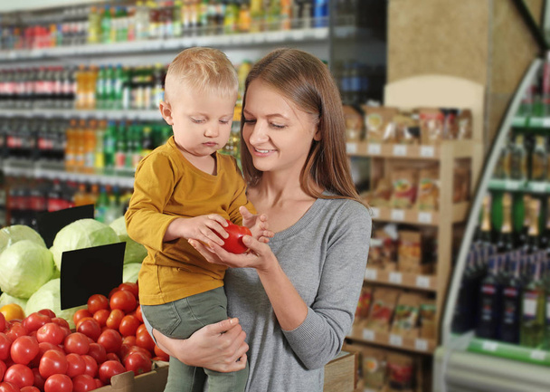 Young mother with little son choosing food in supermarket - Valokuva, kuva