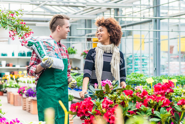 Веселий красивий працівник у квітковому магазині розмовляє з красивим клієнтом
 - Фото, зображення