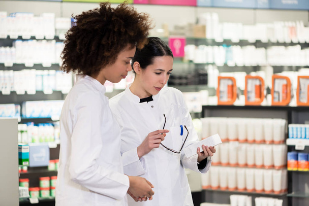 Вид збоку на двох спеціалізованих фармацевтів у сучасній аптеці
 - Фото, зображення