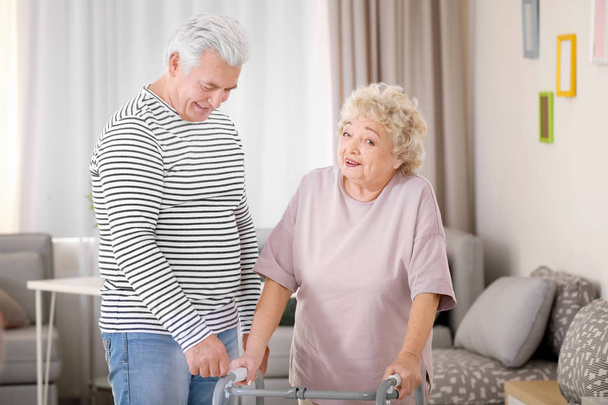 Senior vrouw met wandelaars man praten bij zorg thuis - Foto, afbeelding