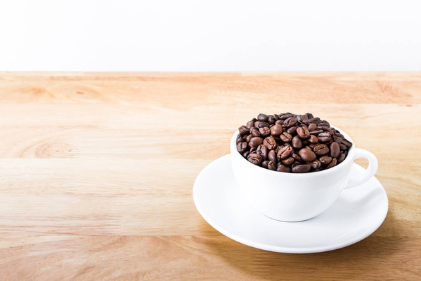 Coffee beans in white cup on wooden table. - Foto, immagini