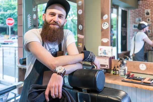 Портрет уверенного молодого парикмахера, улыбающегося в винтажном салоне красоты
 - Фото, изображение