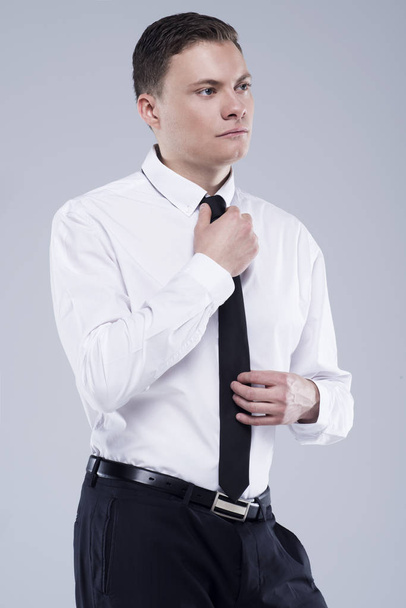 Young handsome man in a shirt with a tie on a light gray background - Fotografie, Obrázek