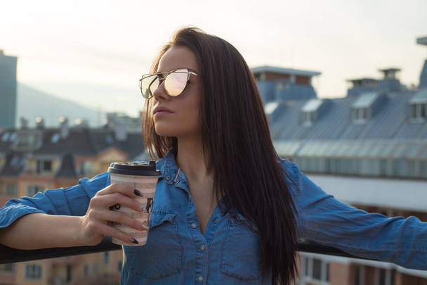Young woman holding coffee cup on balcony - Photo, Image