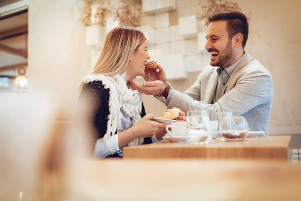 Nuori pari juo kahvia ja syö croissanteja kahvilassa
 - Valokuva, kuva