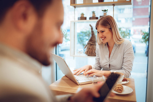 jonge lachende vrouw die op laptop op koffiepauze in café werkt - Foto, afbeelding