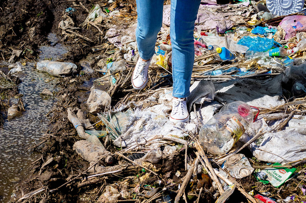 Σωρός από σκουπίδια, κάτω από τα πόδια του κοριτσιού. Ρύπανση του περιβάλλοντος. Εκ - Φωτογραφία, εικόνα