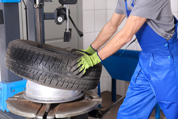 Professional mechanic using modern equipment to change tire in car service center - Foto, afbeelding