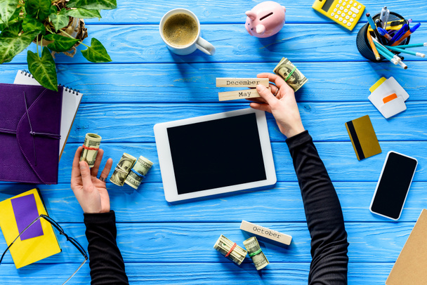 Концепция расходов на планирование с бизнес-человеком, держащим календарь и деньги на синем деревянном столе
 - Фото, изображение