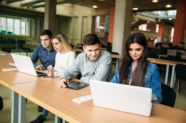 Группа студентов колледжа, обучающихся в школьной библиотеке, девочка и мальчик пользуются ноутбуком и подключаются к интернету
 - Фото, изображение