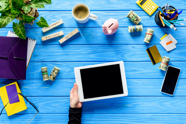 Gros plan de la tablette numérique sur une table en bois bleue avec de l'argent et de la papeterie
 - Photo, image