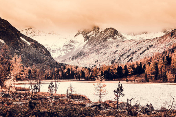 Горное озеро с отражением в зеркальной поверхности скал в облачную дождливую погоду осенью. Красота этой горной страны, природа осенью
. - Фото, изображение