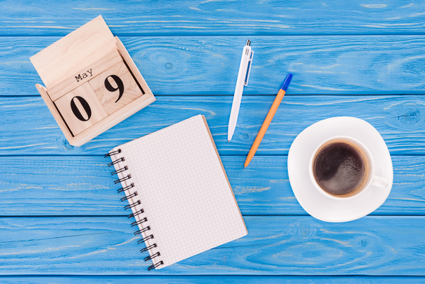 felülnézet fa naptári napja – 9. május, kávéscsésze, üres tankönyv és tollak, győzelem napja koncepció  - Fotó, kép