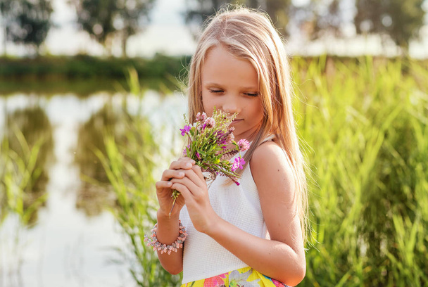 hermosa niña con el pelo largo sostiene flores, al aire libre, retrato
 - Foto, imagen
