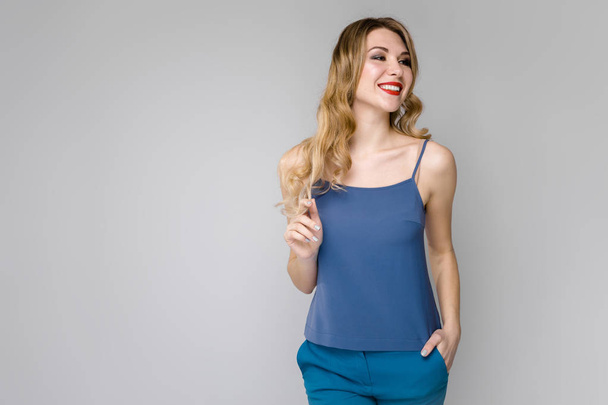Attractive young caucasian blond woman in casual outfit showing different expressions on grey wall in studio.  - Foto, Bild