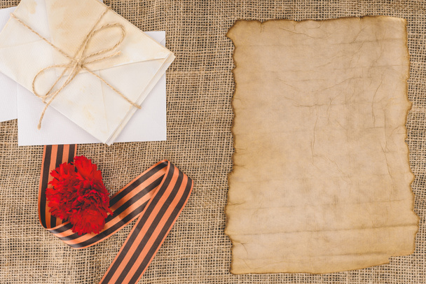 vista superior da fita de São Jorge, cravo, papel velho vazio, pilha de letras
  - Foto, Imagem