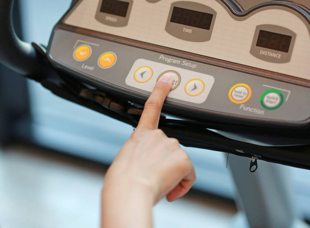 Close up of finger pushing button on treadmill. - Photo, image