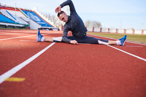 Un deportista hombre realiza una cuerda transversal, en la pista de atletismo del estadio
. - Foto, imagen