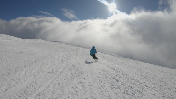 Narciarz alpejski, krótkim huśtawki na nartach na stoku narciarskiego na słoneczne zimowe dni - Materiał filmowy, wideo