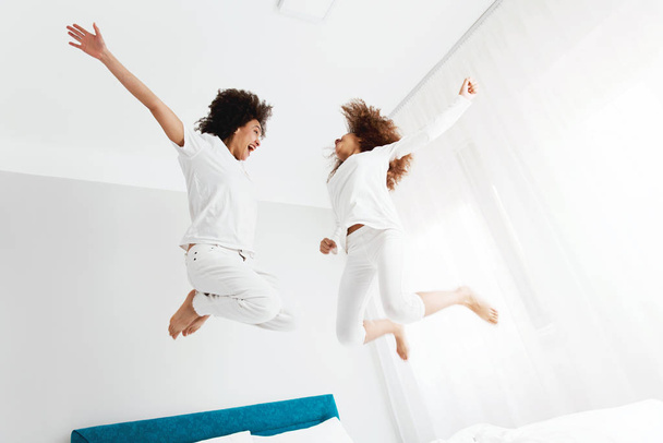 Mother and daughter jumping on the bed, happiness, joyful   - Fotoğraf, Görsel