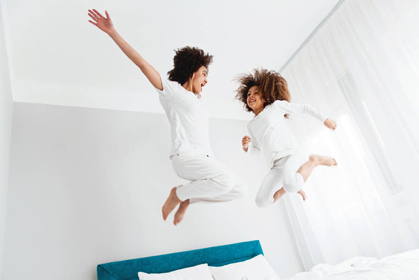 Mother and daughter jumping on the bed, happiness, joyful   - Φωτογραφία, εικόνα