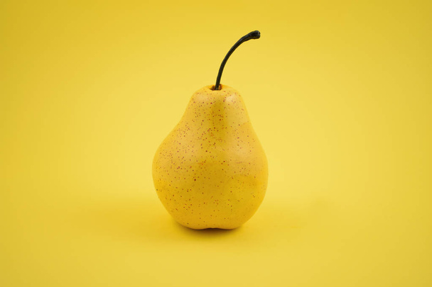 Imágenes de stock de decoración de pera. Pera amarilla sobre fondo amarillo. Decoración casera de pera. Pera decorativa amarilla
 - Foto, imagen