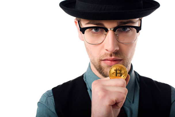Portrait of spy in eyeglasses and hat holding golden bitcoin isolated on white - Φωτογραφία, εικόνα