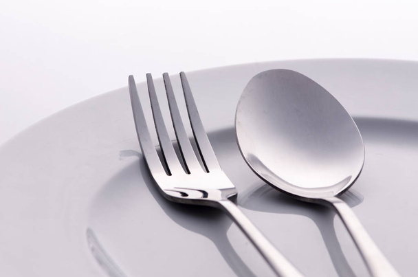 fork and silver spoon on white plate - Foto, Bild