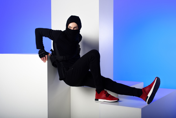 ninja in black clothing standing on white blocks isolated on blue - Zdjęcie, obraz