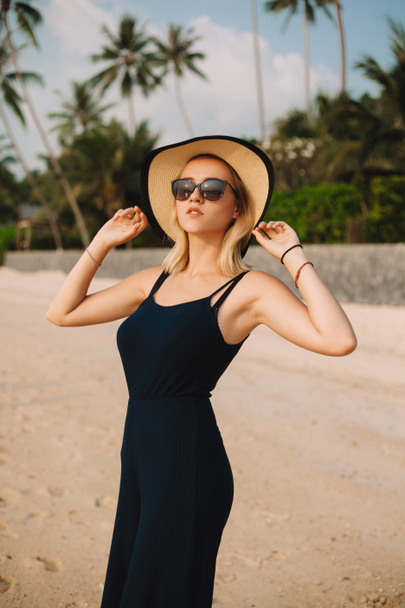 attractive woman in hat and dress looking away on sandy ocean beach - Fotoğraf, Görsel