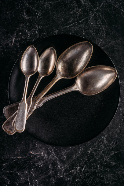 Black plate and vintage spoons on dark background - Foto, immagini