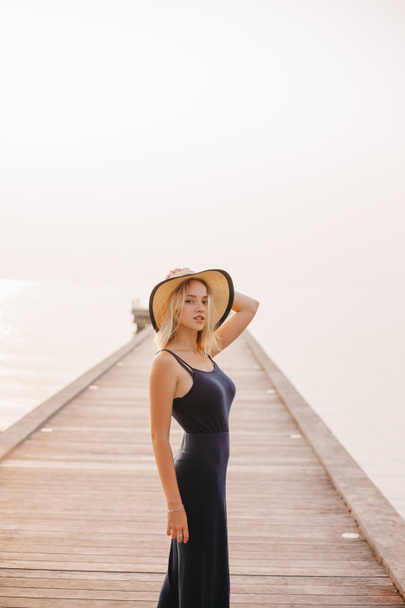 beautiful sensual woman in hat and dress looking at camera near ocean - Valokuva, kuva