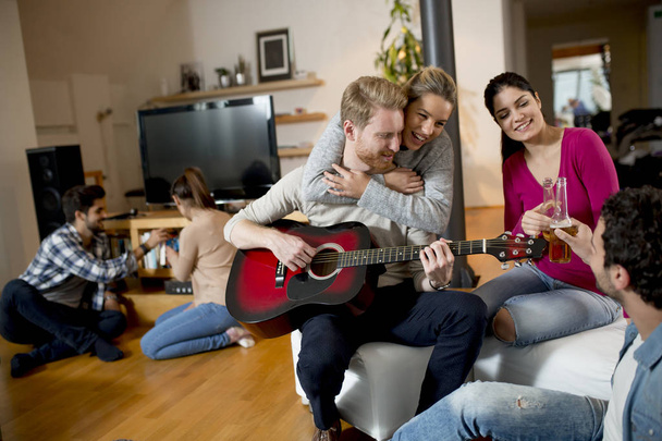 Happy friends playing guitar and listening to music at home - Zdjęcie, obraz