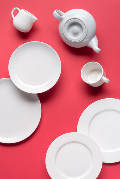 White plates with teapot and cup on red background - Photo, Image