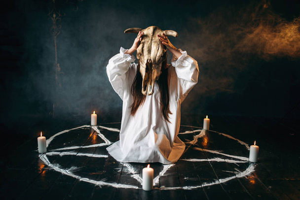 vrouw met dierlijke schedel in handen, pentagram cirkel met kaarsen, ritueel van zwarte magie, occultisme - Foto, afbeelding