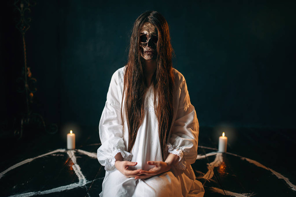 γυναίκα μάγισσα με το κρανίο κεφάλι κάθεται σε πεντάγραμμο κύκλο με κεριά - Φωτογραφία, εικόνα