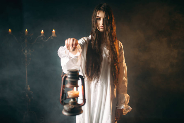 woman in white shirt holding kerosene lamp, black magic ritual, occult and exorcism - Photo, Image