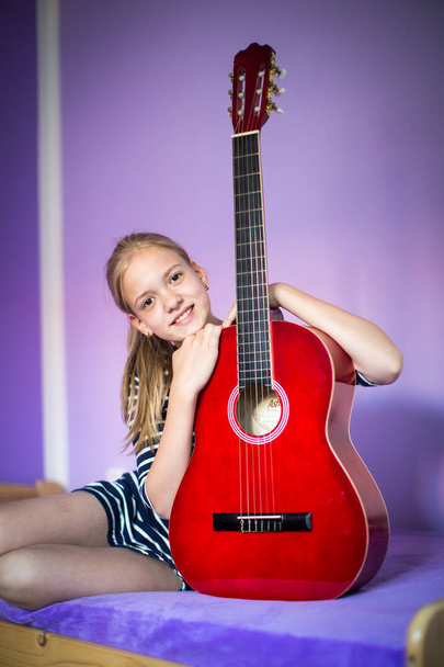 Teenage girl with her guitar in her lovely room - Fotó, kép