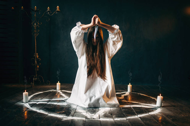 Nainen, jolla on veitsi ja joka istuu pentagrammiympyrässä kynttilöiden, taikarituaalin, okkultismin ja manauksen kanssa, yliluonnollinen voima
 - Valokuva, kuva