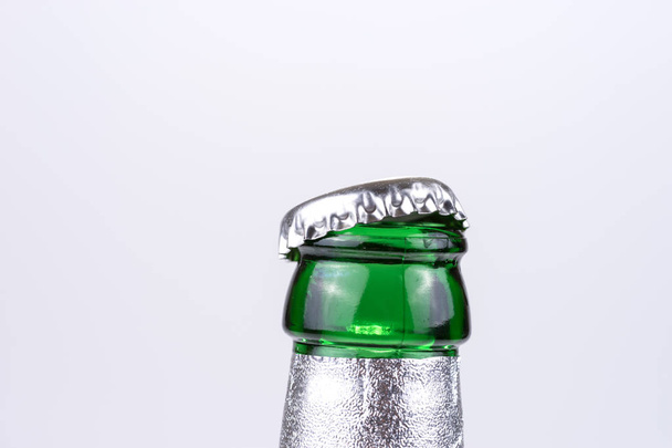Δυσχέρεια και ανοιχτό μπουκάλι καπάκι ενός μπουκαλιού πράσινη beer σε φωτεινό φόντο - Φωτογραφία, εικόνα