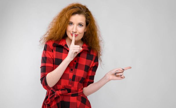 Beautiful curly redhead caucasian woman in red checkered dress showing different emotional expressions on white wall in studio. - Fotoğraf, Görsel