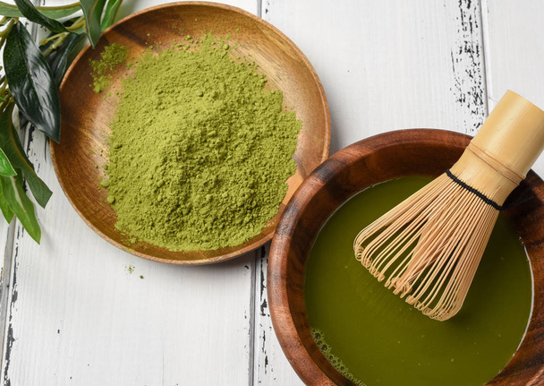 Green tea matcha powder in a wooden bowl with a whisk - Valokuva, kuva
