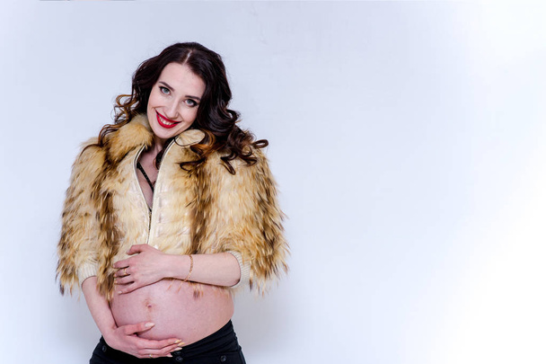beautiful pregnant girl in a fur coat holds on to a naked stomach - Φωτογραφία, εικόνα
